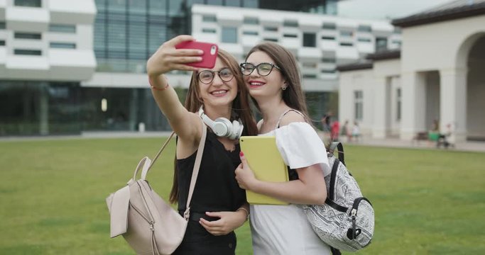 Two young girls taking selfie self portrait photos on smartphone.Female showing positive face emotions