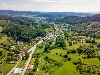Fototapeta na wymiar Drone view over the green forest and small city in mountainous area sunny day in summer season. Carpatians mountains, Romania.