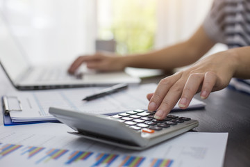 Business woman thinking account, Calculator, Laptop, business chart and graph document on desk.