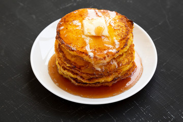 Homemade corn meal Johnny cakes on a white plate on a black surface, side view. Close-up.