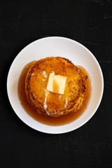 Homemade corn meal Johnny cakes on a white plate on a black background, top view. Flat lay, overhead, from above. Close-up.