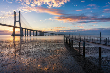 Fototapeta na wymiar Vasco da Gama bridge at sunrise in Lisbon, Portugal. Vasco da Gama Bridge is a cable-stayed bridge flanked by viaducts and rangeviews that spans the Tagus River in Parque das Nações in Lisbon.