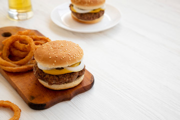 Homemade Mississippi Slug Burgers with onion rings and glass of cold beer on a white wooden background, side view. Copy space.