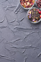 Natural dried tea collection, copy space. Glass bowls with dried herbs, flower buds and tea leaves, top view.