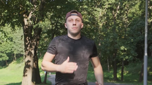 Sport man running in park. Front view of man during morning run. Medium shot of male runer. Sport lifestyle concept