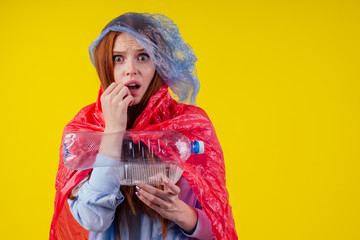 Obraz na płótnie Canvas redhaired ginger european woman wear cloth full of plastic trash in yellow studio background.recycling ecology solution or fast fashion concept