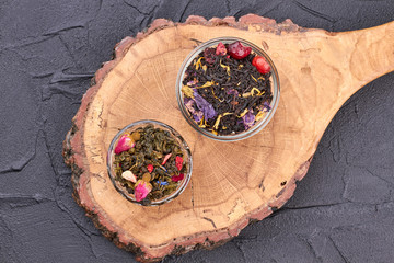 Dried tea on natural tree slice. Bowls with dry tea on vintage cutting board. Food concept.