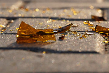 bottle of beer, soda or drugs from dark glass is broken. Shattered beer bottle on ground in sunset light. Fragments of glass on asphalt. Texture, background, wallpaper.