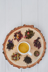 Cup of herbal tea and dry tea on tree slice. Composition with cup of tea on round wooden board. Top view with copy space.