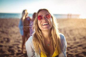 Happy young woman on the beach with her friends in background. Group of friends enjoying on beach...