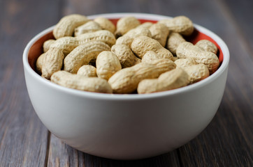 Peanuts on the plate. Dark wooden background. Selective focus