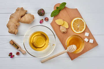 Tea composition on wood background, flat lay. Cup of tea and ingredients for preparation warming beverage. Healthy drink for cold winter.