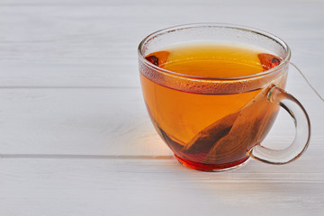 Glass cup of black tea on wooden background. Mug of hot tea on wooden table, horizontal image.