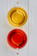 Two cups of tea, top view. Glass cups with green and black ea on white wooden background.