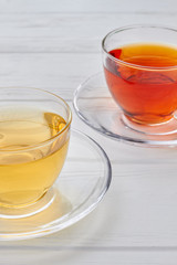 Aromatic tea in cups, cropped image. Glass cups with healthy tea on white wooden background.
