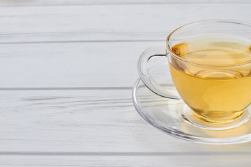 Glass cup with green tea. Herbal tea in transparent cup on wooden background. Space for text.