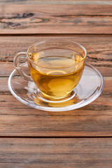 Cup of hot tea on brown wooden background. Aromatic hot tea in glass cup. Healthy herbal beverage.