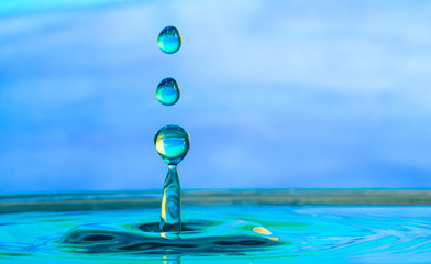 close up of a water drop impacting a body of water on a blue background