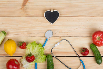 Good healthy and diet concept - Blackboard in shape of heart, stethoscope and vegetables, fruits and berries