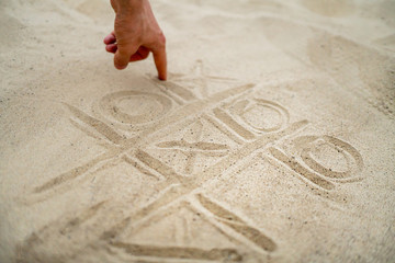 hand drawing tic tac toe playing on the sand in the summer beach