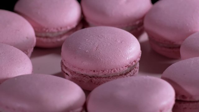 Macaroons rotating on table close-up. Cake macaroon on black background. Macaroon cookies slow rotates.