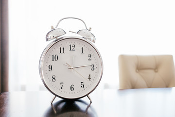 Old retro alarm clock on wooden table with pastel background. Time change concept