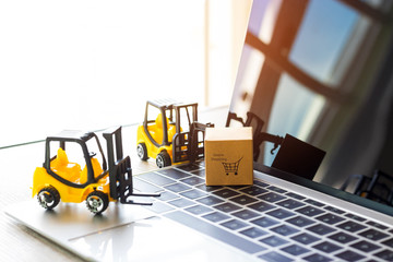 Mini forklift truck and cardboard box with text online shopping on laptop keyboard. Logistics and transportation management ideas and Industry business commercial concept.