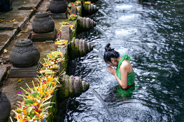 Woman pray and bath holy spring waters in Tirta Empul water temple, Bali, Indonesia.