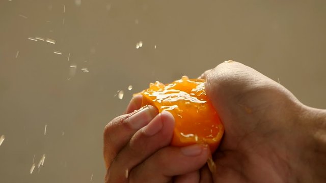 Male hand squeezing fresh orange juice in slow motion. Hand squeezing an orange.