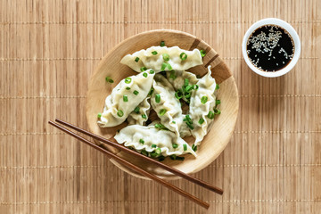 Asian dumplings in bowl, chopsticks, rustic wood background. Chinese dumplings for dinner.