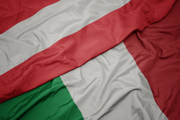 waving colorful flag of italy and national flag of austria.