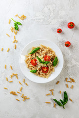 Pasta with tomatoes and basil on a white plate. Italian traditional cuisine.
