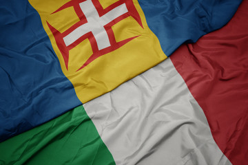 waving colorful flag of italy and national flag of madeira.