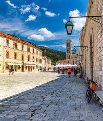 Main square in old medieval town Hvar. Hvar is one of most popular tourist destinations in Croatia in summer. Central Pjaca square of Hvar town, Dalmatia, Croatia. - obrazy, fototapety, plakaty
