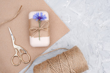 Packaging of natural handmade soap, decorated kraft paper , blue flower, skein of twine and scissors. Concept of organic cosmetics. Top view Flat lay Copy space Template for design