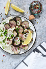 Smoked mackerel with onions and lemon on a concrete background. View from above.