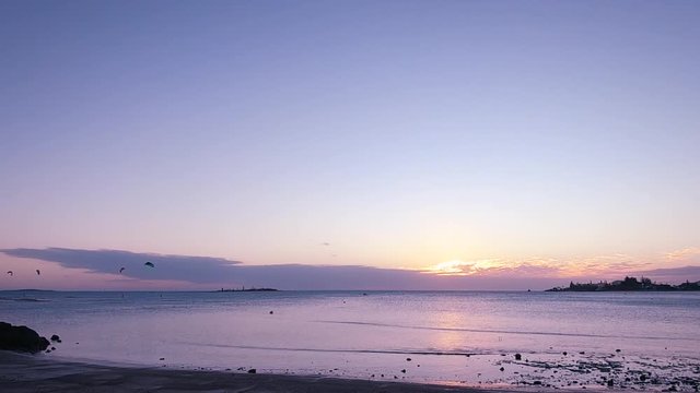 Calm and beautiful sunset time lapse video with wind surfers in the background at Anse Vata Bay in Noumea, New Caledonia, French Polynesia, South Pacific ocean.