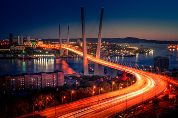 Fototapeta na wymiar Cityscape overlooking the Golden bridge in blue hour. Bright illumination adorns the night city.