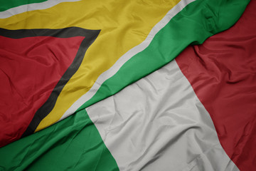 waving colorful flag of italy and national flag of guyana.