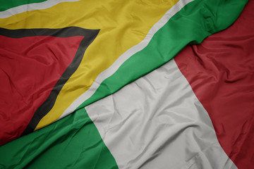 Obraz premium waving colorful flag of italy and national flag of guyana.