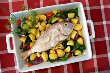 casserole with fresh gilthead sea bream with vegetable and herbs as top view. Raw dorado fish with spices and vegetables on the table. Diet vegetarian food. Dorado Royale Fish