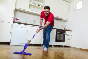  Young man washing floor on the kitchen