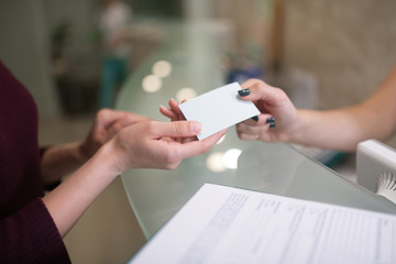 Close up of receptionist giving name card of dentist for client