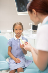 Girl sitting on dental chair and listening to doctor attentively