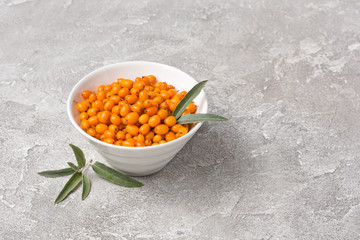 Fresh ripe sea buckthorn berries in white bowl