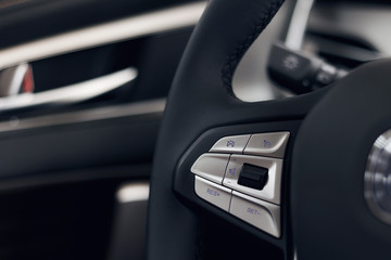 Fototapeta na wymiar Multimedia leather steering wheel in a modern expensive car. Perforated leather steering wheel. Modern car interior details. Car detailing. Selective focus