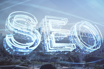 SEO hologram on city view with skyscrapers background double exposure. Search optimization concept.