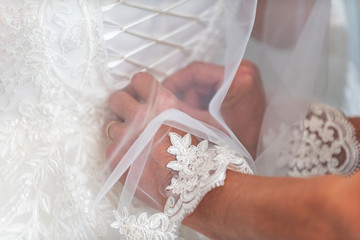 Mother hands helping with bride's white corset