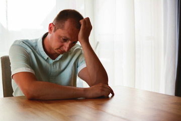 Fototapeta premium Feeling Down. Middle aged man looking down. Portrait of pensive worried man looking through the table and thinking. Pensive male..