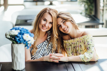 Family, parenthood, communication and people concept - happy motherwith her young girl having dinner and talking at restaurant or cafe.